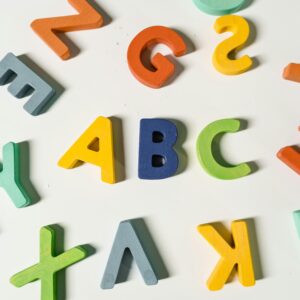 Bright, colorful wooden alphabet letters scattered on a surface ideal for children's learning.